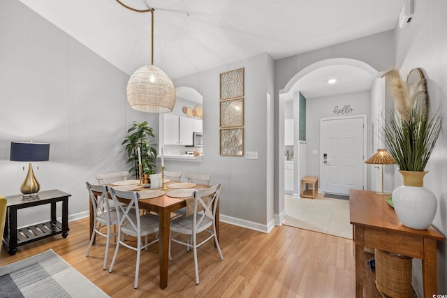 dining area with arched walkways, light wood-style flooring, and baseboards