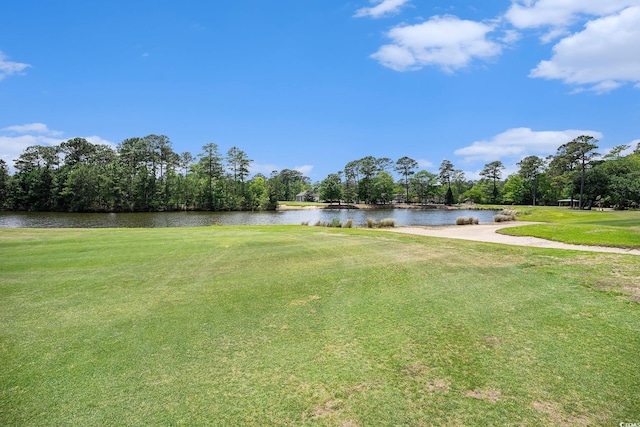 view of grassy yard featuring a water view, view of golf course, and view of wooded area
