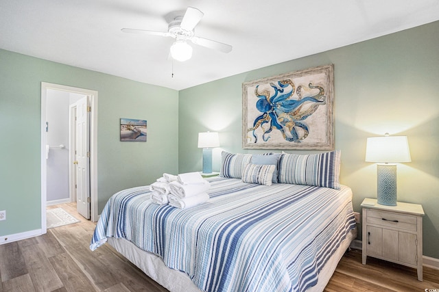 bedroom with wood finished floors, baseboards, ensuite bathroom, and a ceiling fan