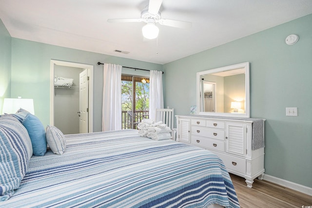 bedroom with wood finished floors, baseboards, access to exterior, a spacious closet, and a ceiling fan