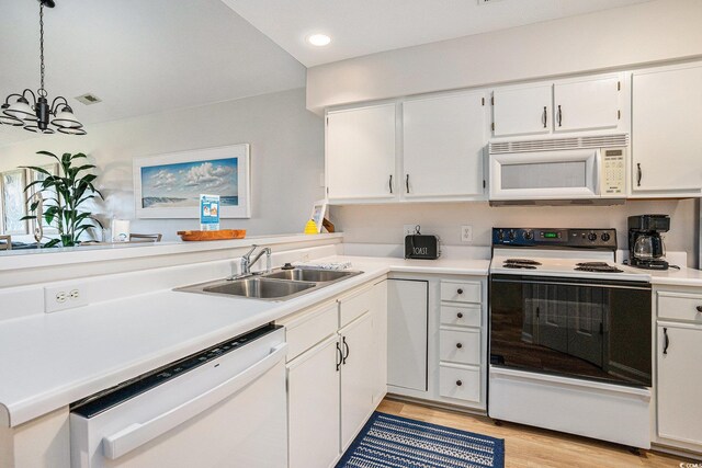 kitchen featuring white appliances, a sink, a chandelier, light wood-style floors, and white cabinetry