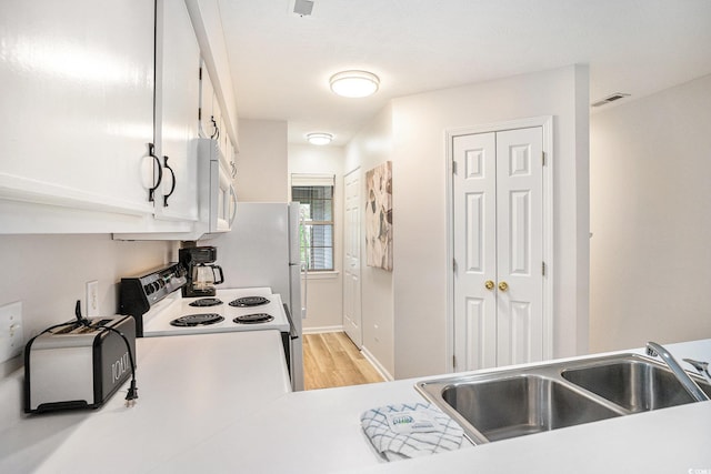 342 Pinehurst Ln Unit 12J, Pawleys Island, SC 29585 - kitchen featuring white microwave, a sink, electric range, light wood-style flooring, and white cabinets