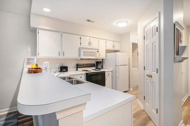kitchen featuring white appliances, light wood-style flooring, a peninsula, light countertops, and a sink