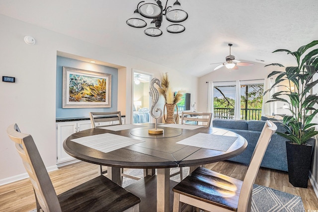 dining room with light wood-style flooring, a chandelier, vaulted ceiling, ceiling fan, and baseboards