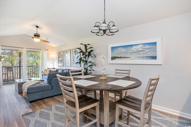 dining space featuring vaulted ceiling, wood finished floors, ceiling fan, a chandelier, and baseboards