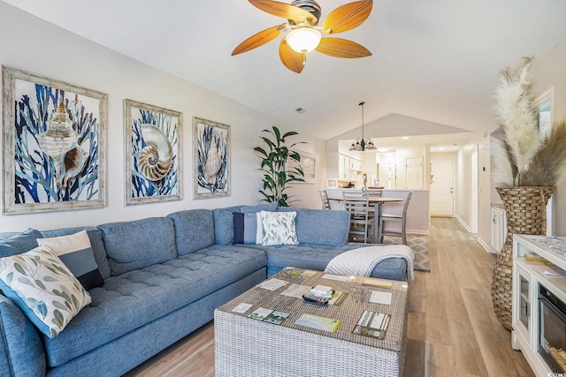living room with light wood-style floors, vaulted ceiling, ceiling fan, and a chandelier
