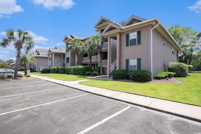 view of front of property with uncovered parking, a front lawn, and stairs