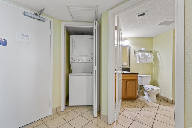 504 N Ocean Blvd N Unit 309, Myrtle Beach, SC 29577 - laundry area featuring stacked washer and clothes dryer, light tile patterned floors, baseboards, and a textured ceiling