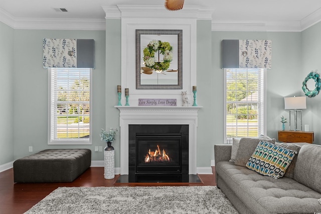 living area with crown molding, wood finished floors, a fireplace with flush hearth, and baseboards