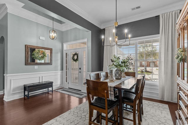 dining area featuring a chandelier, healthy amount of natural light, ornamental molding, wood finished floors, and arched walkways