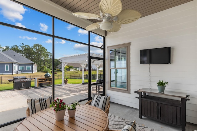 sunroom featuring outdoor dining space, a ceiling fan, and a residential view