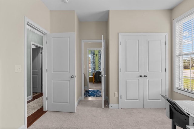 carpeted bedroom with a closet, multiple windows, and baseboards