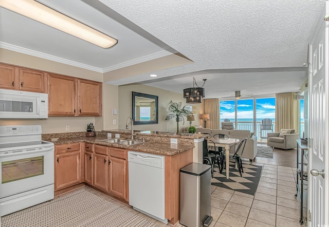 kitchen with white appliances, open floor plan, a peninsula, a sink, and light tile patterned flooring