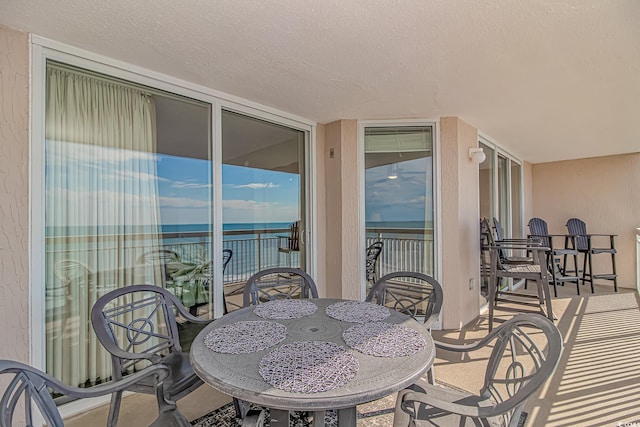 balcony with a water view and outdoor dining area