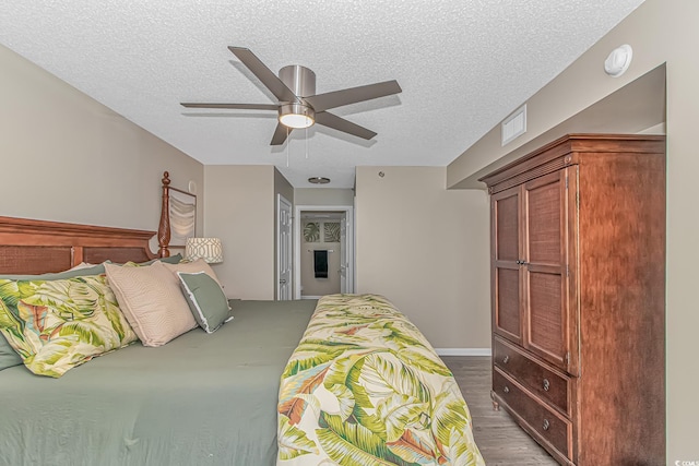bedroom with a textured ceiling, a ceiling fan, and wood finished floors