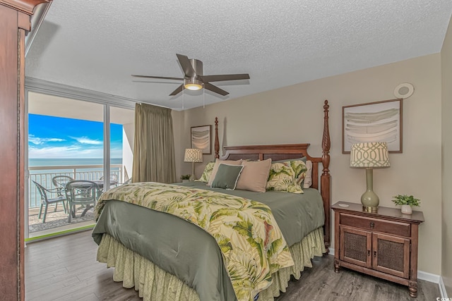 bedroom with access to exterior, wood finished floors, a water view, a textured ceiling, and a ceiling fan