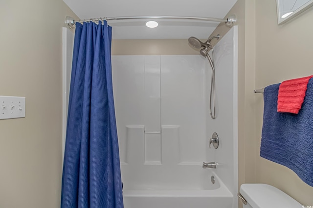 bathroom featuring toilet and shower / bath combination with curtain