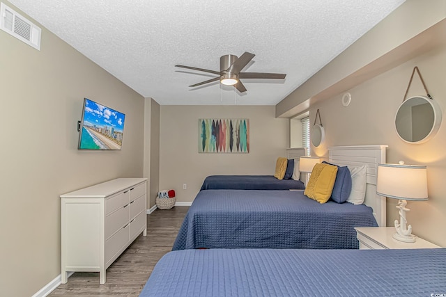 bedroom with a textured ceiling, light wood-type flooring, baseboards, and ceiling fan