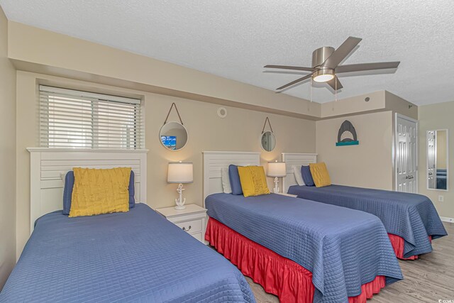 bedroom featuring wood finished floors, a textured ceiling, a ceiling fan, and baseboards