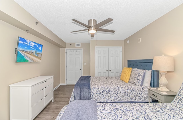 bedroom with wood finished floors, a textured ceiling, a closet, a ceiling fan, and baseboards