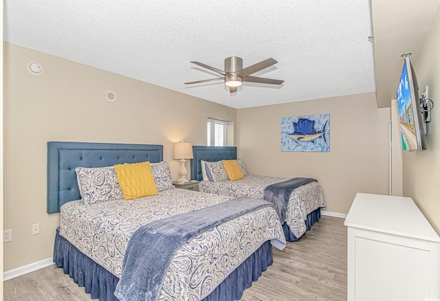 bedroom featuring light wood finished floors, a textured ceiling, baseboards, and ceiling fan