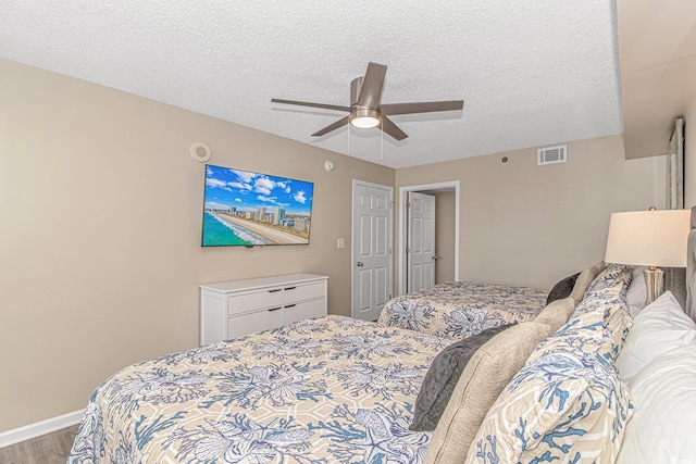 bedroom featuring wood finished floors, a textured ceiling, ceiling fan, and baseboards