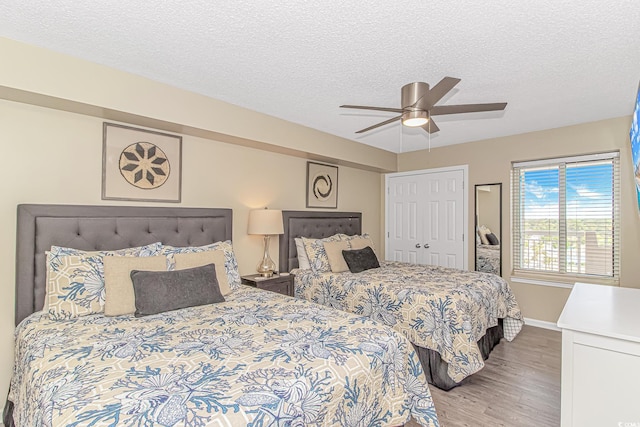 bedroom featuring light wood-style floors, baseboards, a textured ceiling, ceiling fan, and a closet