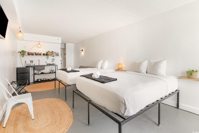 bedroom featuring finished concrete flooring and baseboards