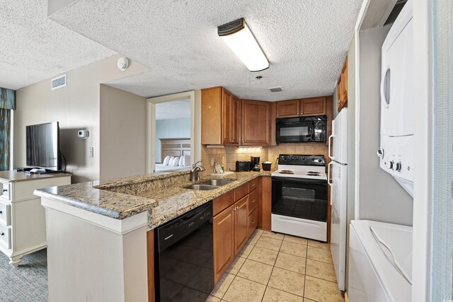 2701 N Ocean Blvd Unit 1260, Myrtle Beach, SC 29577 - kitchen with black appliances, a sink, stacked washer and clothes dryer, a peninsula, and decorative backsplash