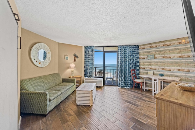 living area with expansive windows, dark wood finished floors, a textured ceiling, and a water view