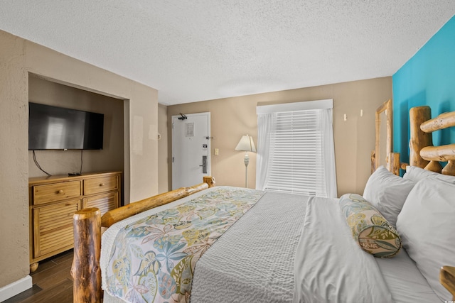 bedroom with dark wood-style flooring, a textured ceiling, and baseboards