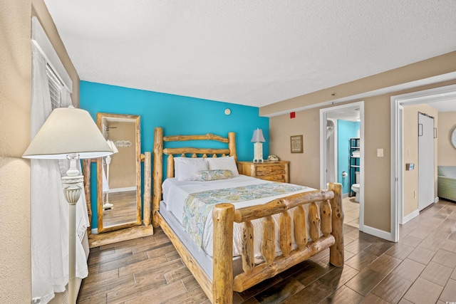 bedroom featuring wood tiled floors, baseboards, and a textured ceiling