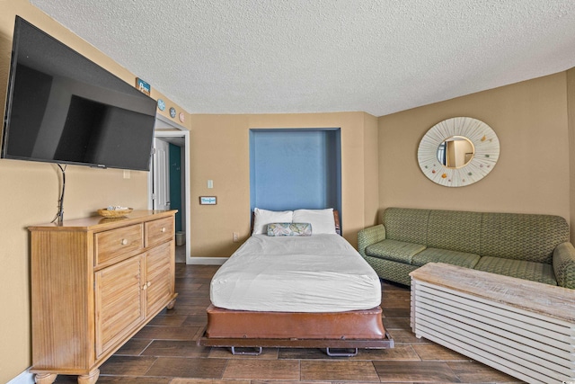 bedroom featuring a textured ceiling, dark wood-style floors, and baseboards