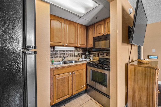 kitchen with black appliances, a sink, light countertops, backsplash, and light tile patterned flooring