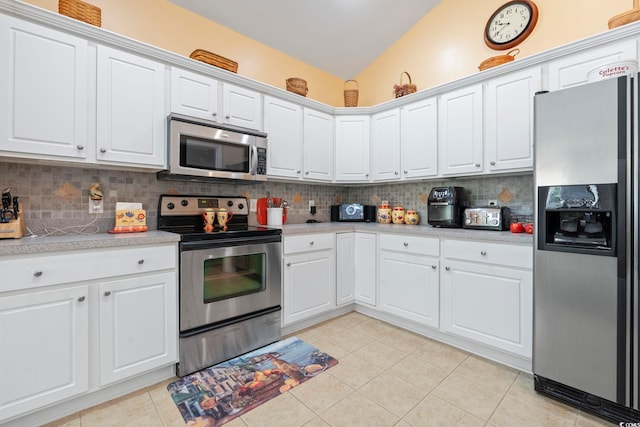 kitchen with appliances with stainless steel finishes, light countertops, decorative backsplash, white cabinetry, and vaulted ceiling