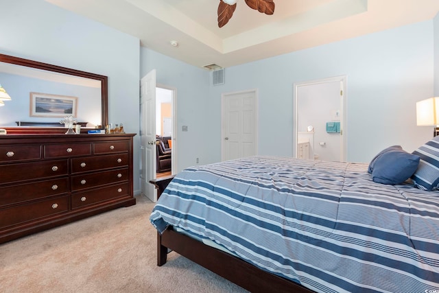bedroom featuring light carpet, ensuite bathroom, and a ceiling fan