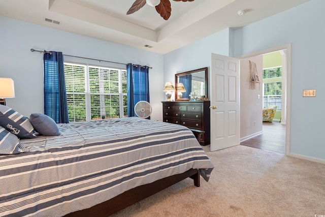 bedroom with light colored carpet, baseboards, ceiling fan, and a raised ceiling