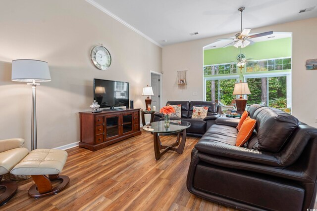 living area with a towering ceiling, a ceiling fan, light wood-style floors, ornamental molding, and baseboards