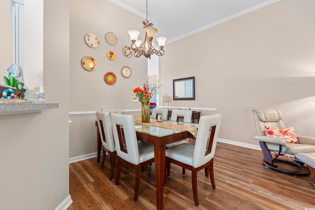 dining space featuring ornamental molding, wood finished floors, a chandelier, and baseboards