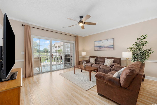 living area featuring a ceiling fan, light wood-style floors, crown molding, and baseboards