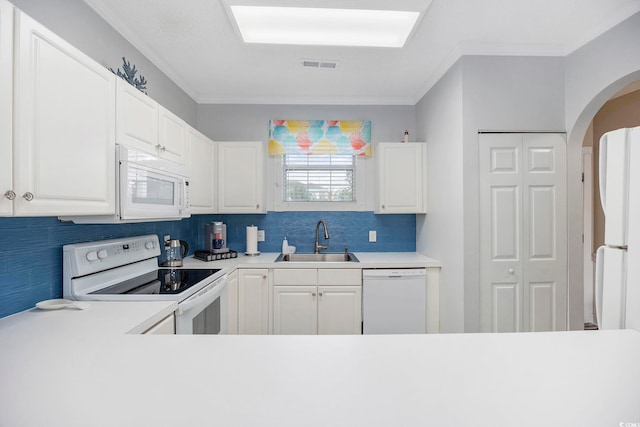 kitchen featuring white appliances, a sink, light countertops, arched walkways, and tasteful backsplash