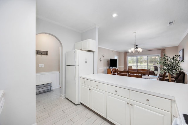 kitchen featuring freestanding refrigerator, crown molding, white cabinetry, light countertops, and a chandelier