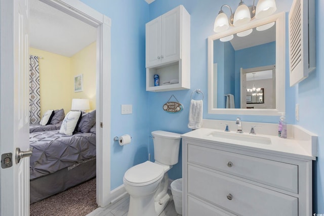 ensuite bathroom with a chandelier, toilet, and vanity