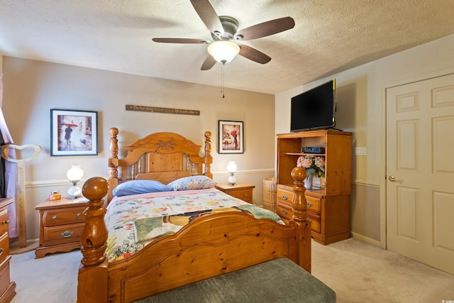 bedroom featuring light carpet, a textured ceiling, and ceiling fan