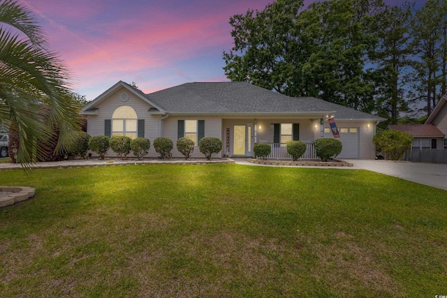ranch-style home featuring covered porch, a garage, driveway, and a front lawn