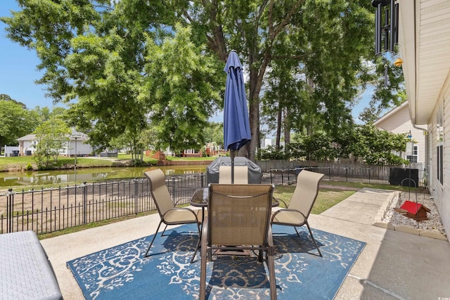 view of patio featuring a water view, fence, and outdoor dining space