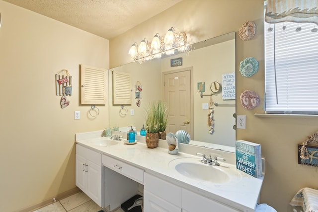 bathroom featuring a textured ceiling, double vanity, and baseboards