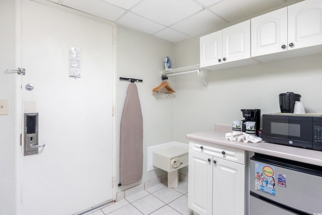 6803 N Ocean Blvd Unit 228, Myrtle Beach, SC 29572 - kitchen with black microwave, freestanding refrigerator, white cabinetry, light tile patterned floors, and a drop ceiling