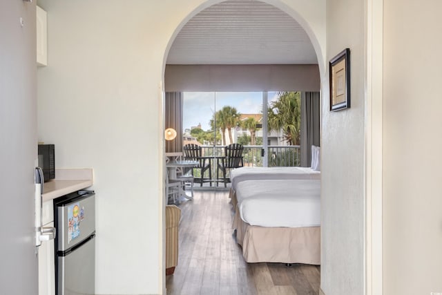 6803 N Ocean Blvd Unit 228, Myrtle Beach, SC 29572 - bedroom with freestanding refrigerator, arched walkways, wood finished floors, and access to exterior