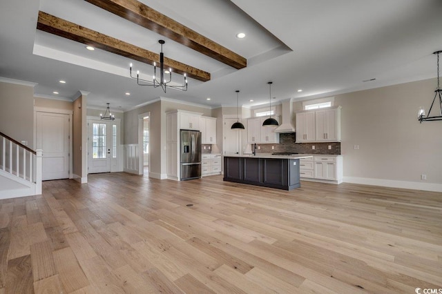kitchen featuring a chandelier, open floor plan, stainless steel fridge, custom range hood, and ornamental molding
